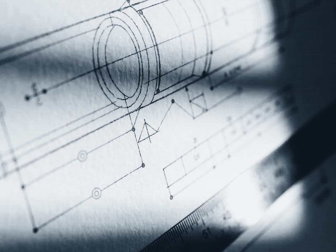 Close-up of a printed technical drawing showing a section detail with leader lines, a datum triangle and a geometric tolerance feature-control frame, with a steel rule across the lower edge.