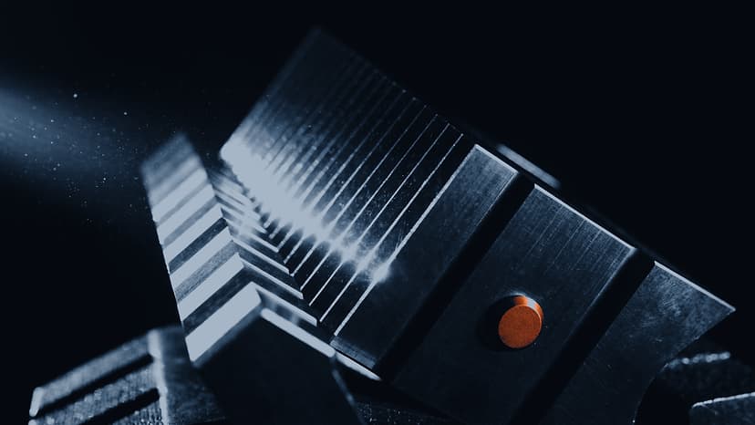 A machined steel fixture under hard raking light: a row of milled fins throwing hard-edged shadows across a deep black background, with a single copper fastener seated in the flycut face of the block.