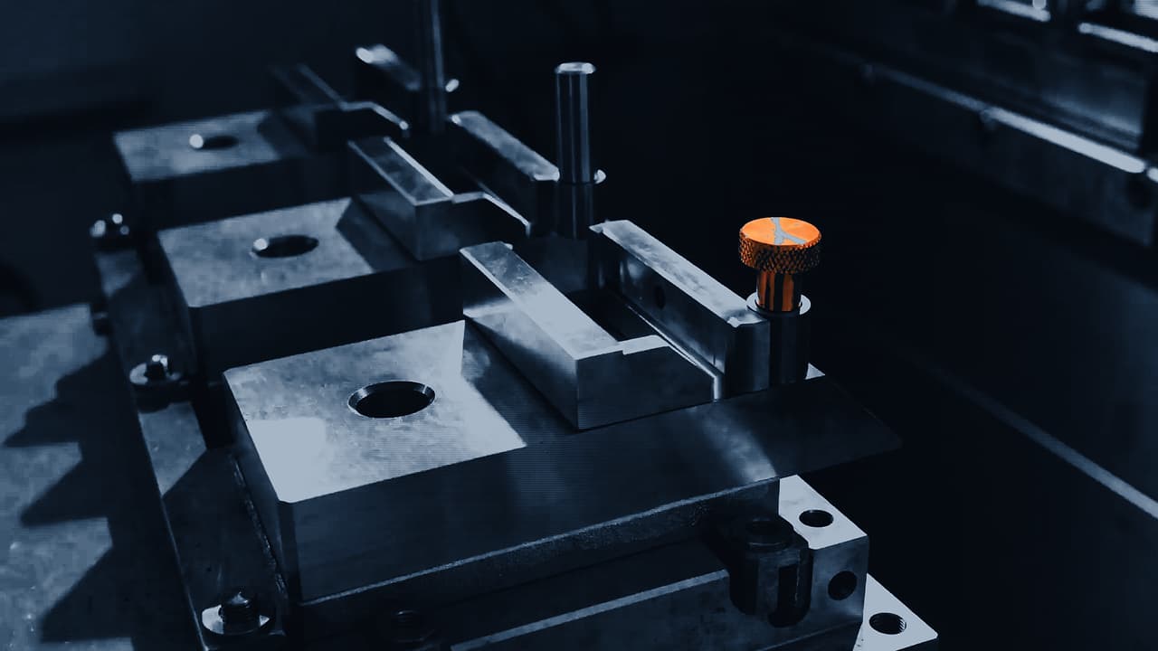 A steel workholding fixture bolted to a machine table, with toe clamps and dowel-located rest pads, the part pocket empty.